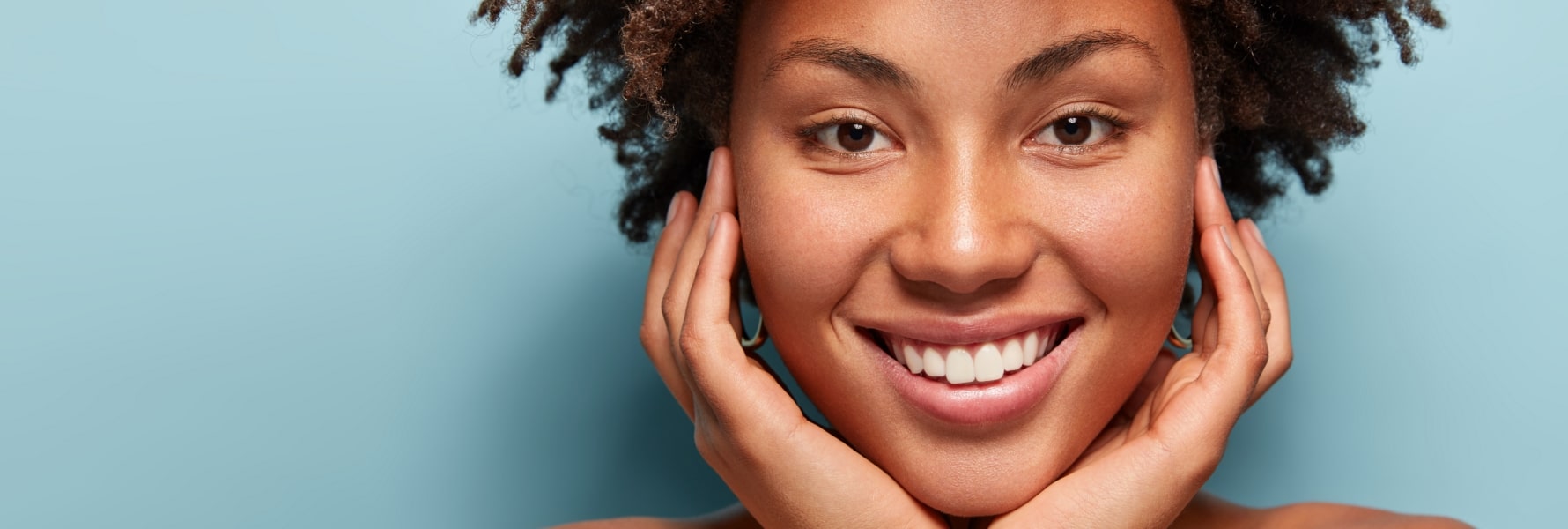 close-up image of a woman smiling at the camera after getting actinic keratosis treatment