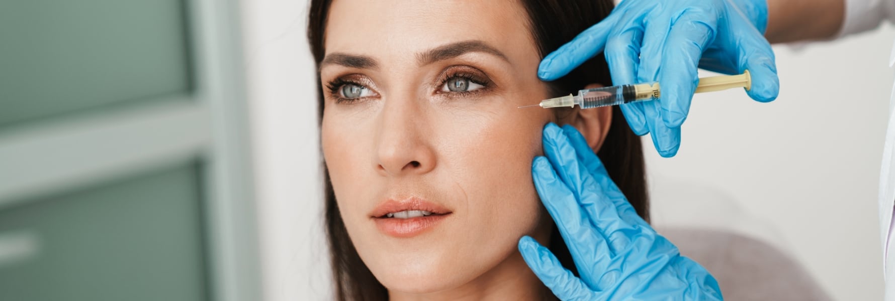 woman receiving Botox injection near eye from professional in blue gloves