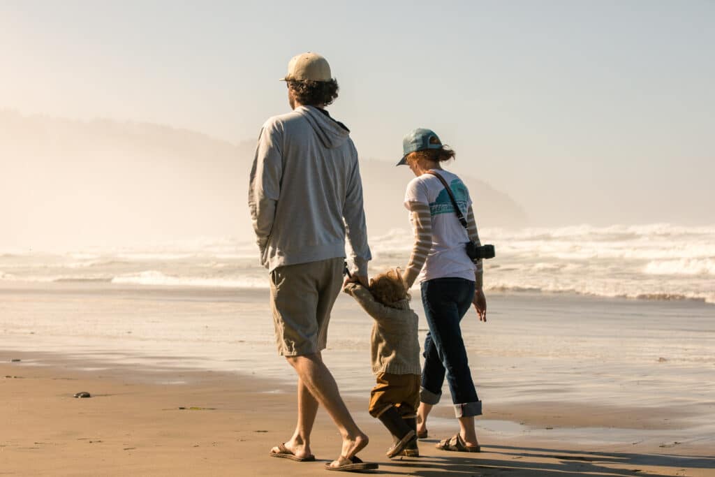 Family walking on florida beach wearing hats, sunglasses, and protective clothing to avoid sun damage