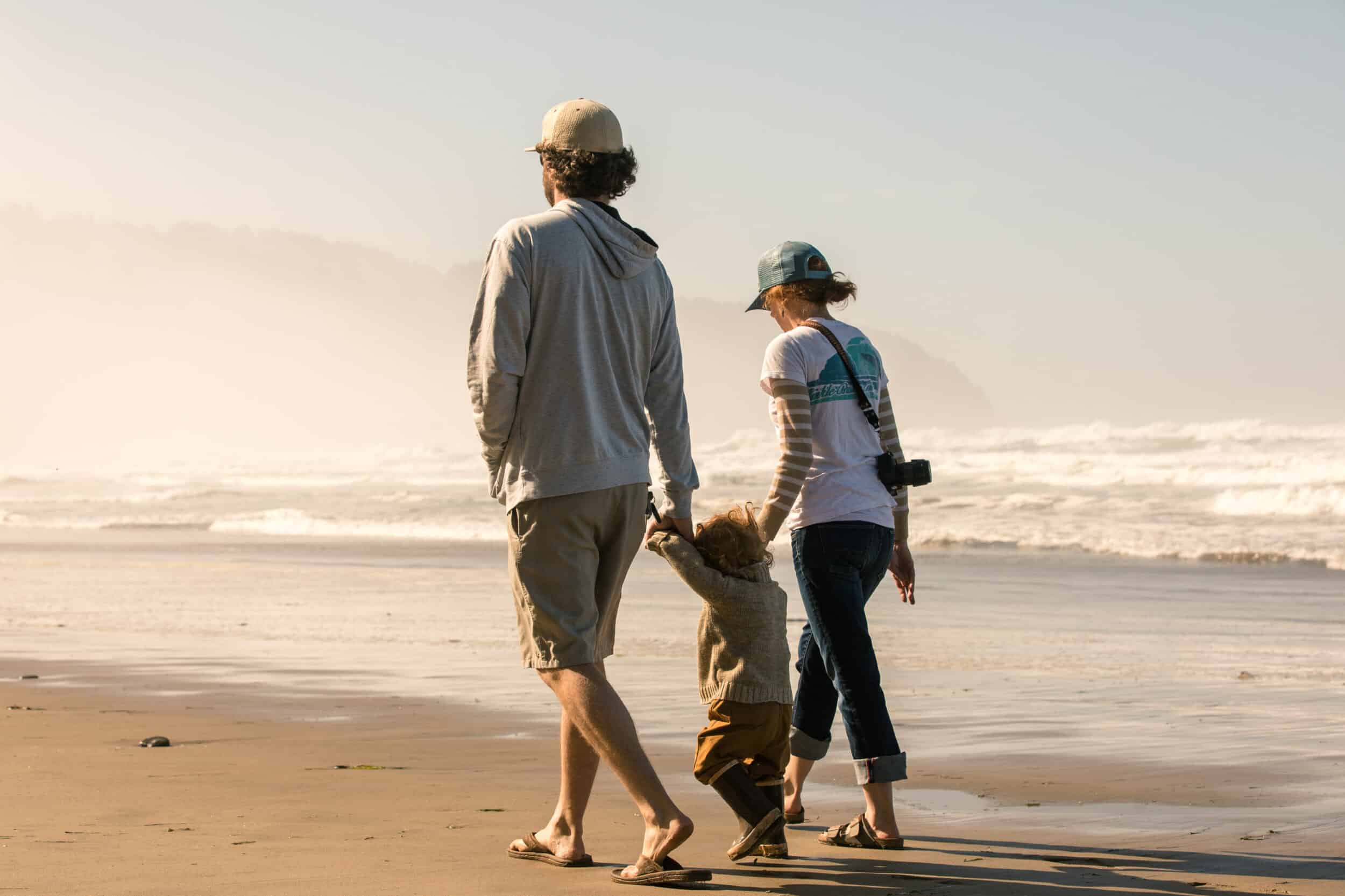Family walking on florida beach wearing hats, sunglasses, and protective clothing to avoid sun damage