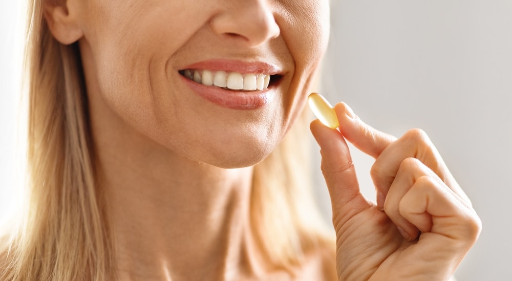 Woman smiles and holds a collagen supplement for beautiful skin.
