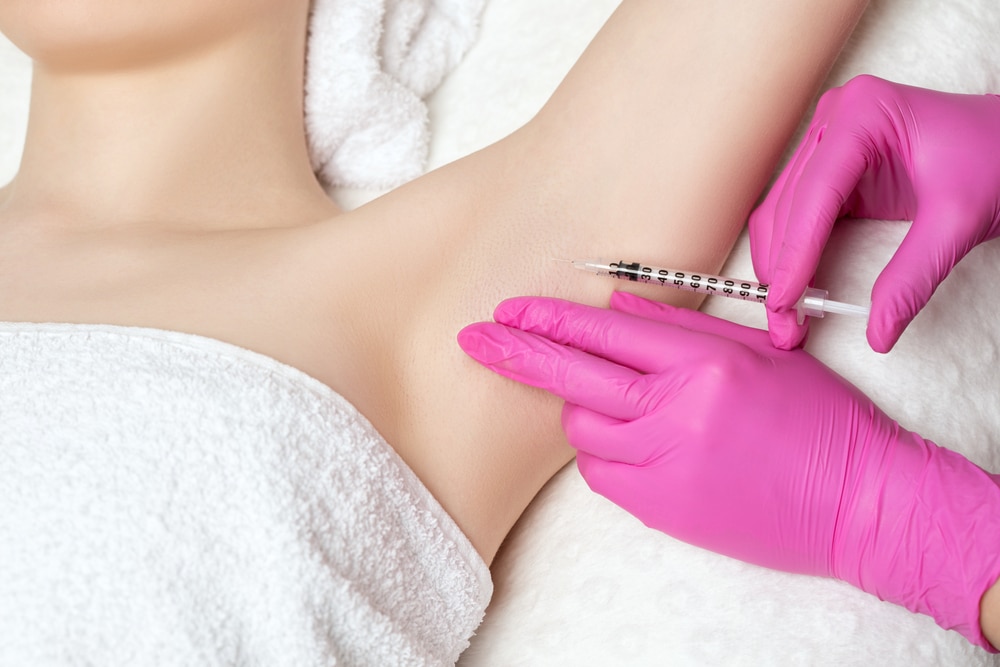 Woman exposes her underarm as a doctor injects Botox to treat hyperhidrosis